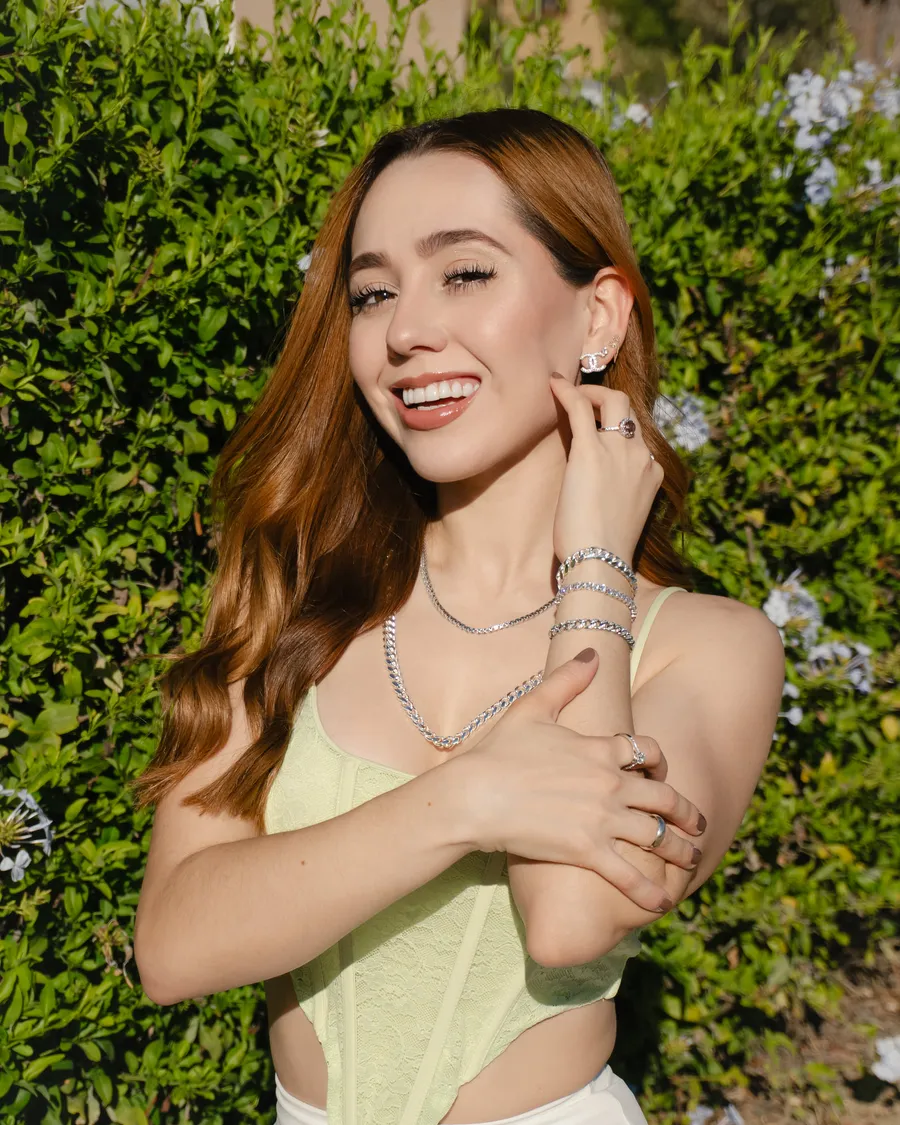 Model wearing layered silver necklaces and stacked rings