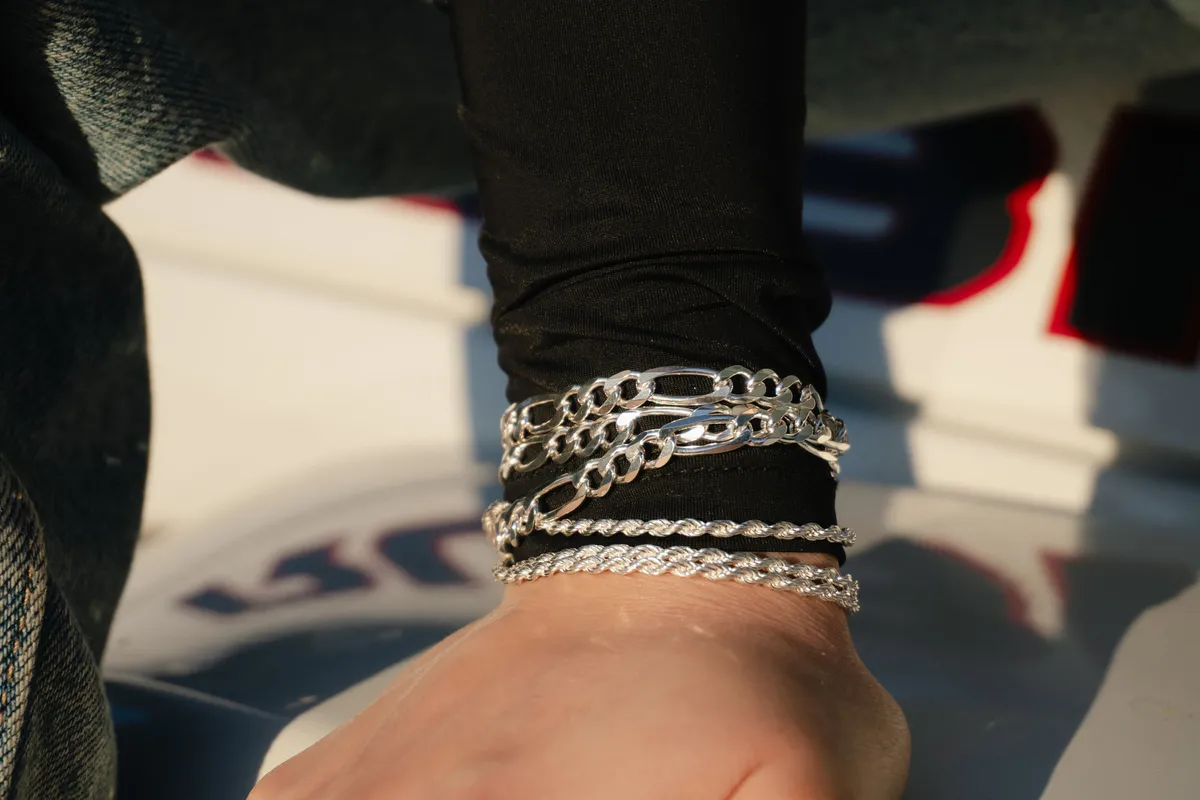 Wrist stacked with silver tennis and curb-link bracelets